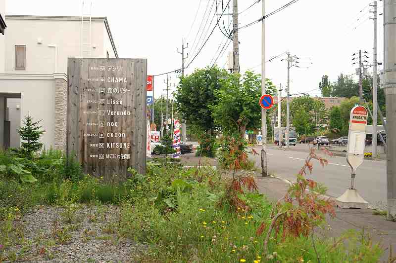 旭神ヴィレッジ箱庭の看板と、そのすぐ前にバス停が置かれている