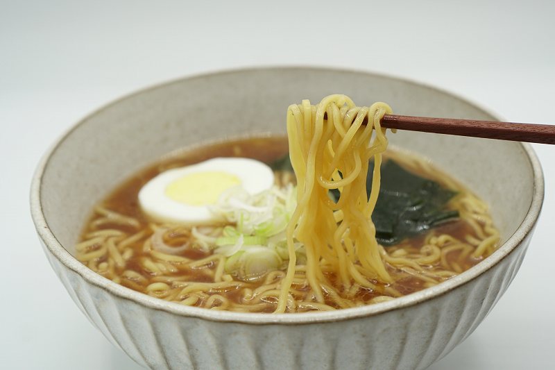 天金の袋ラーメンの麺を箸で持ち上げている様子