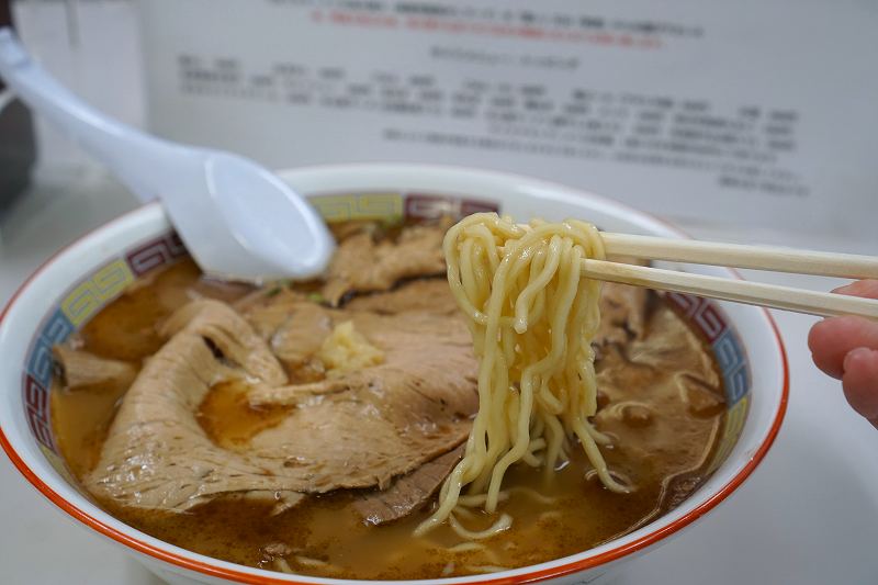 ラーメンの蜂屋五条創業店の「しょうゆチャーシュー（税込1000円）」の麺を箸で持ち上げている様子