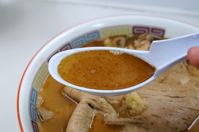 ラーメンの蜂屋五条創業店の「しょうゆチャーシュー(税込1000円)」のスープをれんげですくっている様子