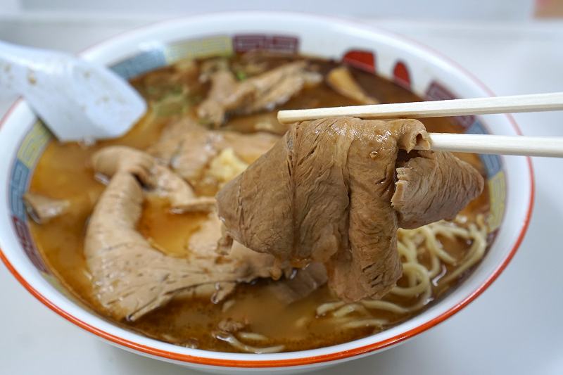 ラーメンの蜂屋五条創業店の「しょうゆチャーシュー（税込1000円）」のチャーシューを箸で持ち上げている様子