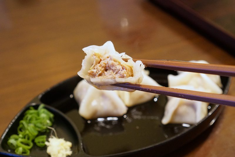 半分にカットされたすぎ餃子を箸で持ち上げている様子