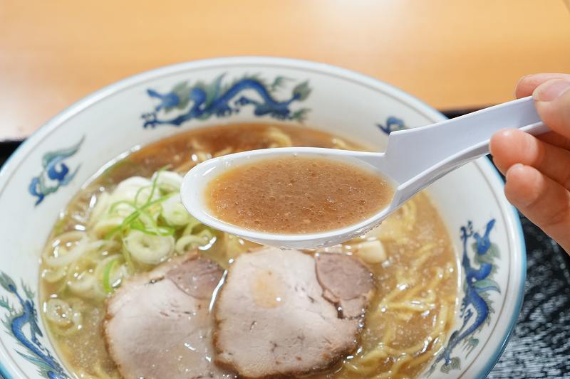 らーめんや天金の正油ラーメンのスープをれんげですくっている様子