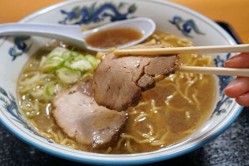 らーめんや天金の正油ラーメンのチャーシューを箸で持ち上げている様子