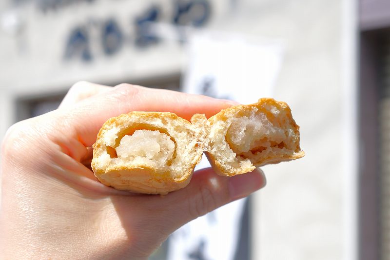 バナナ焼・たい焼 だるまや の半分に割った「バナナ焼(税込170円)」を手に持っている様子