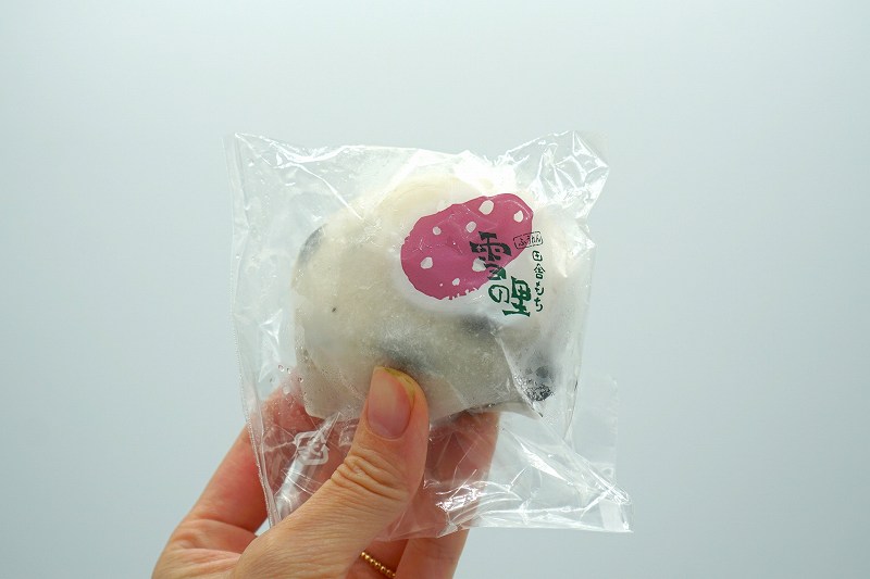 「田舎もち雪の里（塩豆大福）税込155円」を手に持っている様子