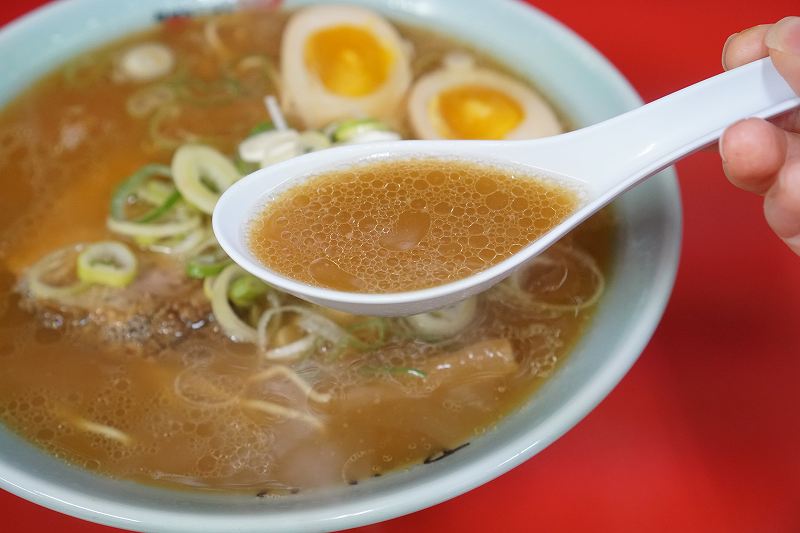 梅光軒 旭川本店の醤油ラーメンのスープをれんげですくっている様子