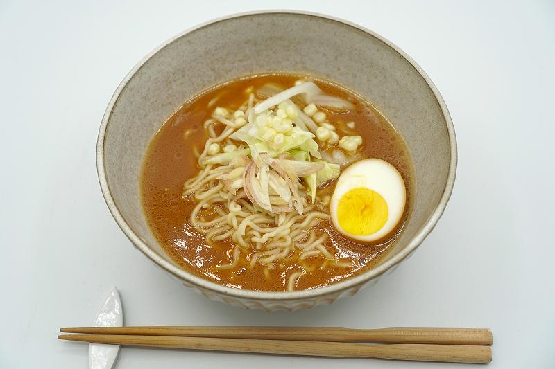 コーンやみょうが、ゆで卵がトッピングされた梅光軒の生ラーメンがテーブルに置かれている