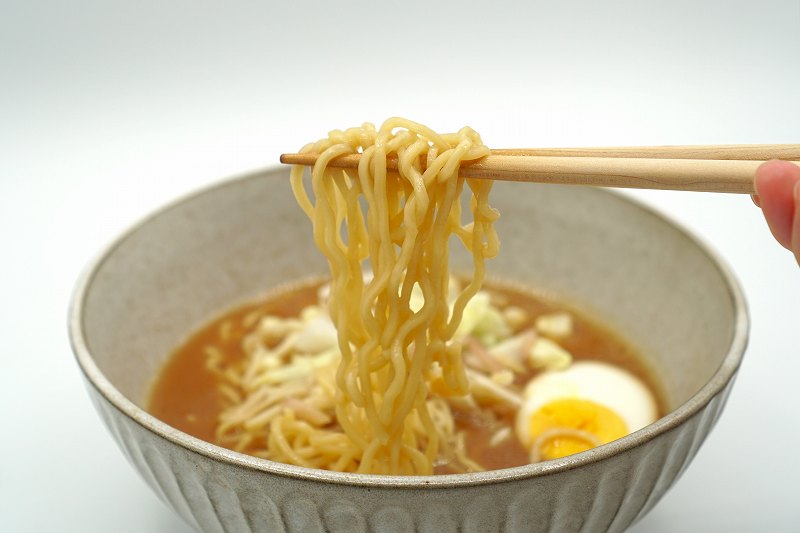 梅光軒の生ラーメンの麺を箸で持ち上げている様子