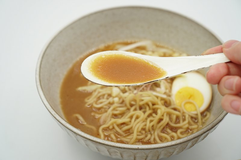 梅光軒の生ラーメンのスープをれんげですくっている様子