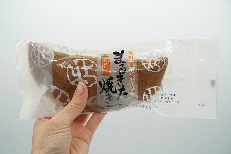 菓子処まるきたの中華まんじゅう「まるきた焼き(税込360円)」を手に持っている様子