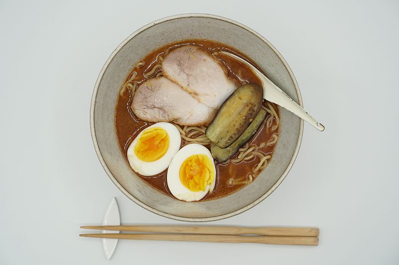 どんぶりに盛り付けられた旭川ラーメン 蜂屋のおみやげ生ラーメンがテーブルに置かれている