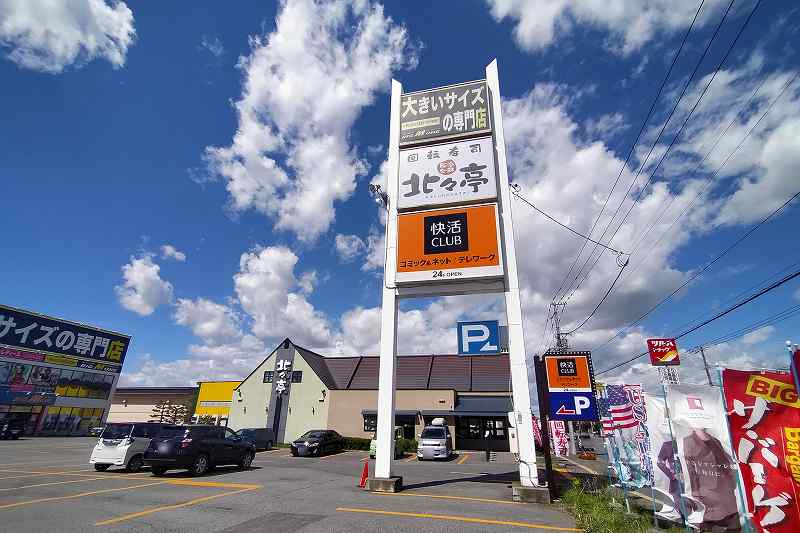 北々亭、快活CLUB、大きいサイズの専門店の看板が駐車場内に建っている様子