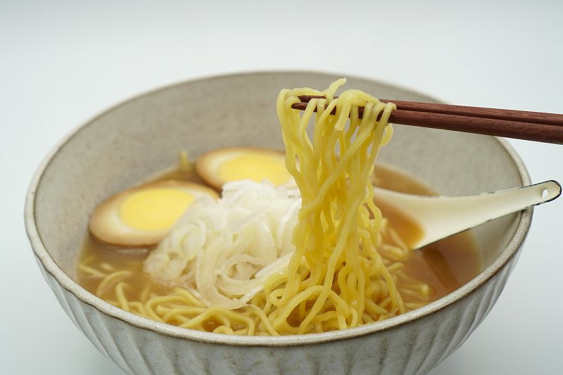 梅光軒の袋ラーメンの麺を箸で持ち上げている様子