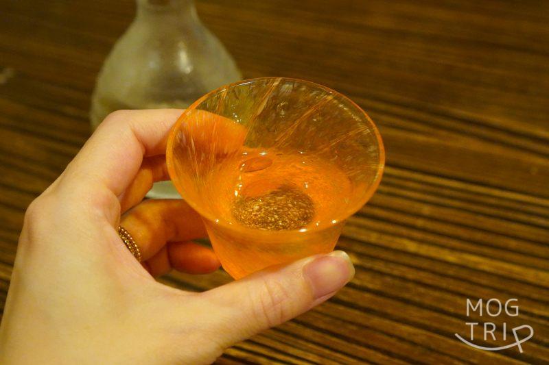 旭川「鮨みなと」の日本酒を手に持っている様子