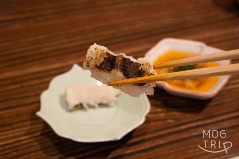 旭川「鮨みなと」の「焼きハモ」を箸で持ち上げている様子