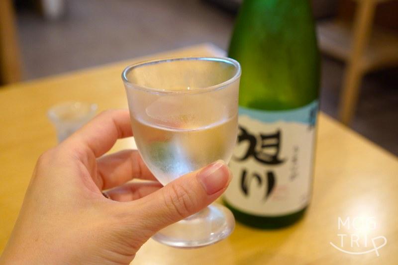 旭川「小西鮨」の日本酒を手に持っている様子